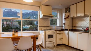 A kitchen with a stove, oven, and a view of mountains through large windows.