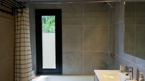 Un baño moderno con bañera, ducha y un espejo grande.