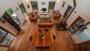 Un salon spacieux doté d’un plancher en bois, de canapés en cuir, d’une table basse centrale et d’une cheminée.