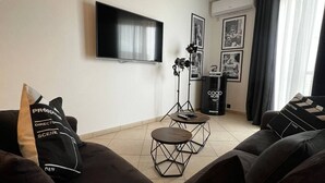 A living room with a TV, two tables, and a sofa. - Trendy Seaside Escape |Designer Finished Penthouse

 (Wied il-Ghajn)