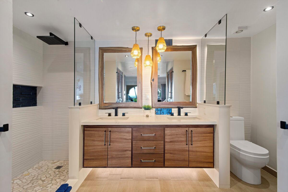 Un baño moderno con un espejo grande, tocador de madera y zona de ducha.