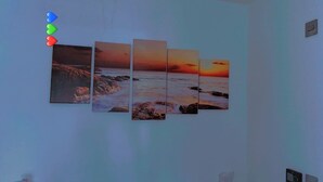 Un mur orné d’une série de tableaux représentant un coucher de soleil sur l’océan.