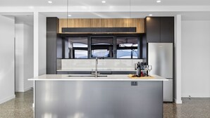 Una cocina moderna con una isla central, electrodomésticos de acero inoxidable y vistas a la montaña a través del ventanal.