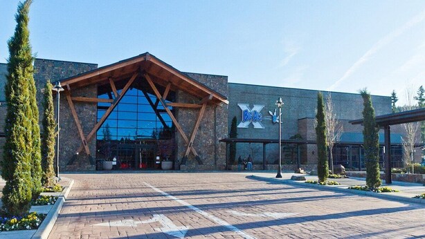A modern building with a large glass facade and a wooden entrance canopy. - Cozy Fall Retreat w/ Swim Spa (Tigard)