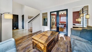 A spacious living room with a wooden coffee table, a blue sofa, and a staircase leading to another room. - Cozy Fall Retreat w/ Swim Spa (Tigard)