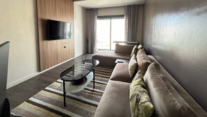 Ein modernes Wohnzimmer mit einer Couch, einem Glastisch und einem an der Wand befestigten Flachbildfernseher.