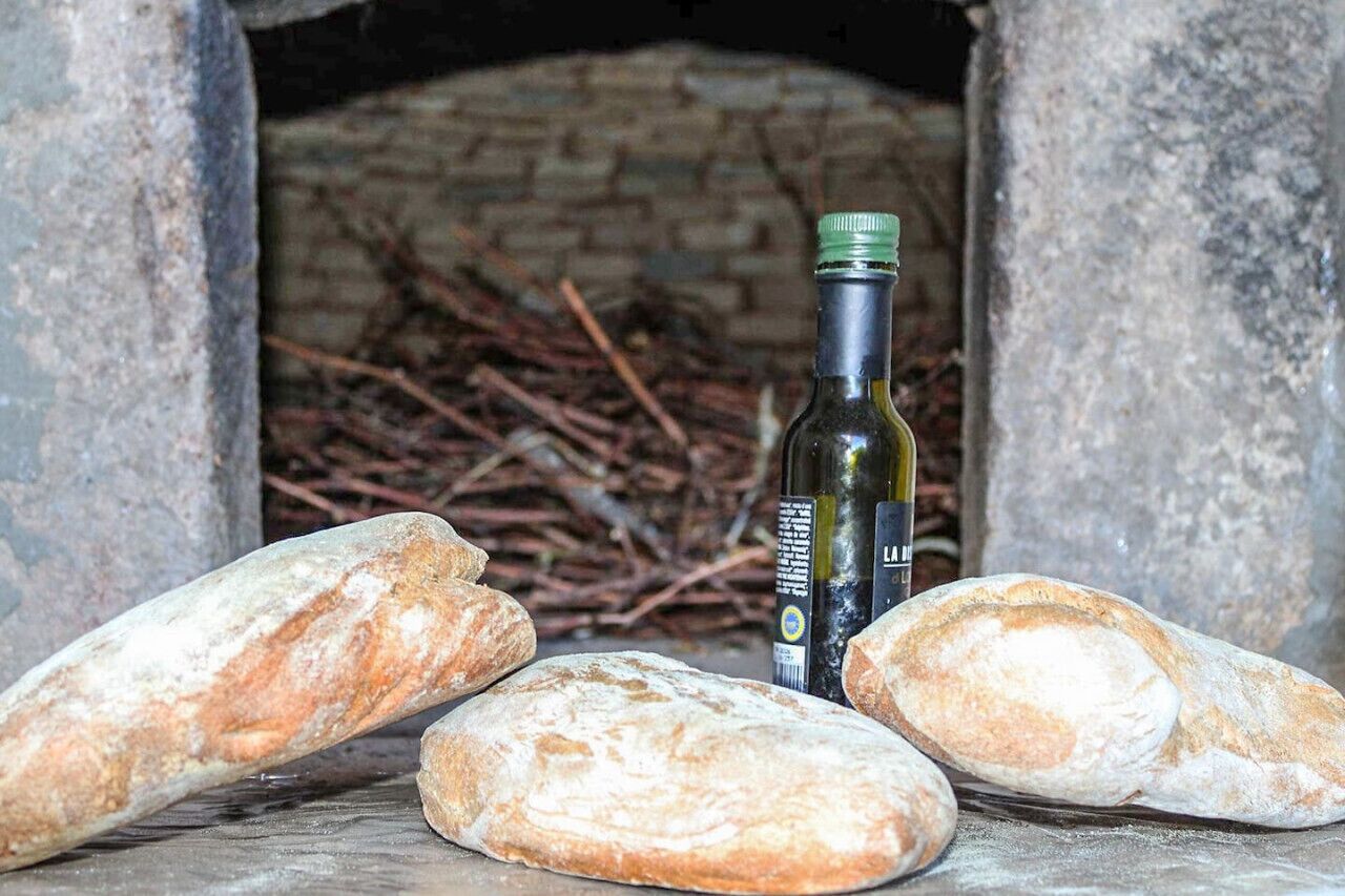 Un four en pierre, du pain et une bouteille d’huile d’olive.