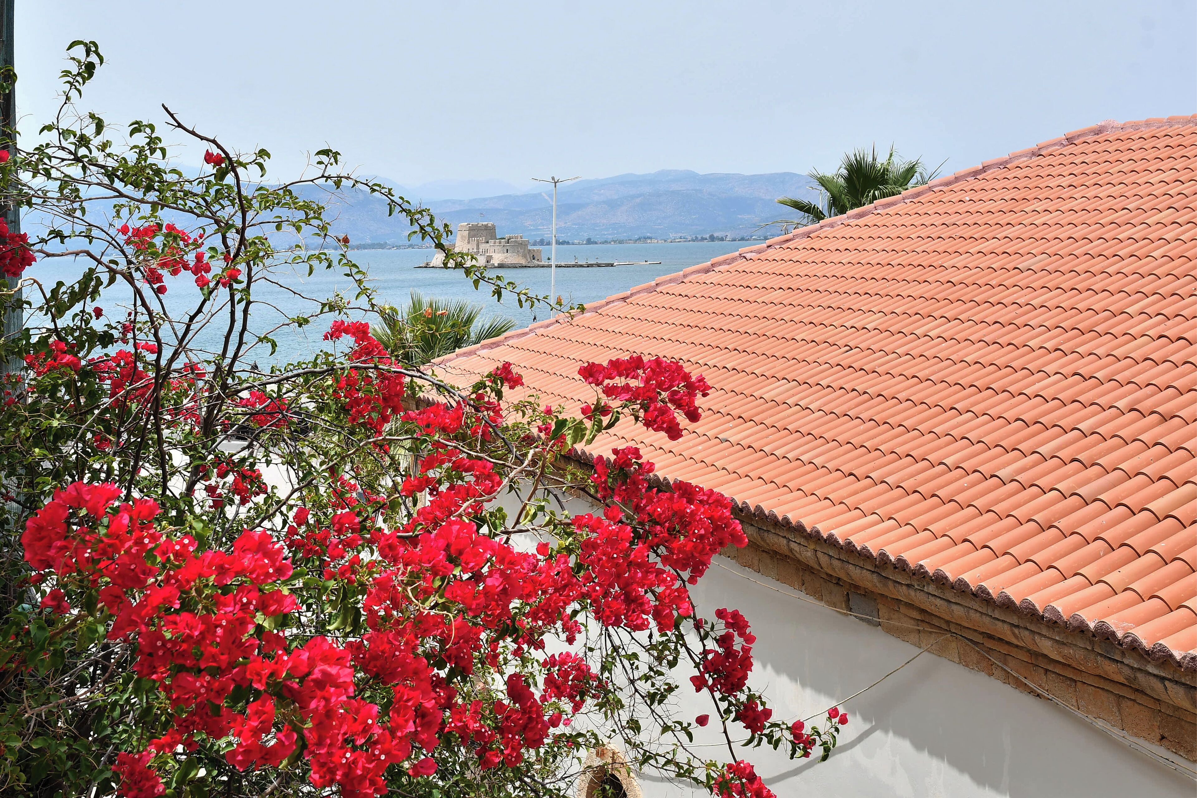 Um edifício com telhado de telhas vermelhas e vista para o mar.