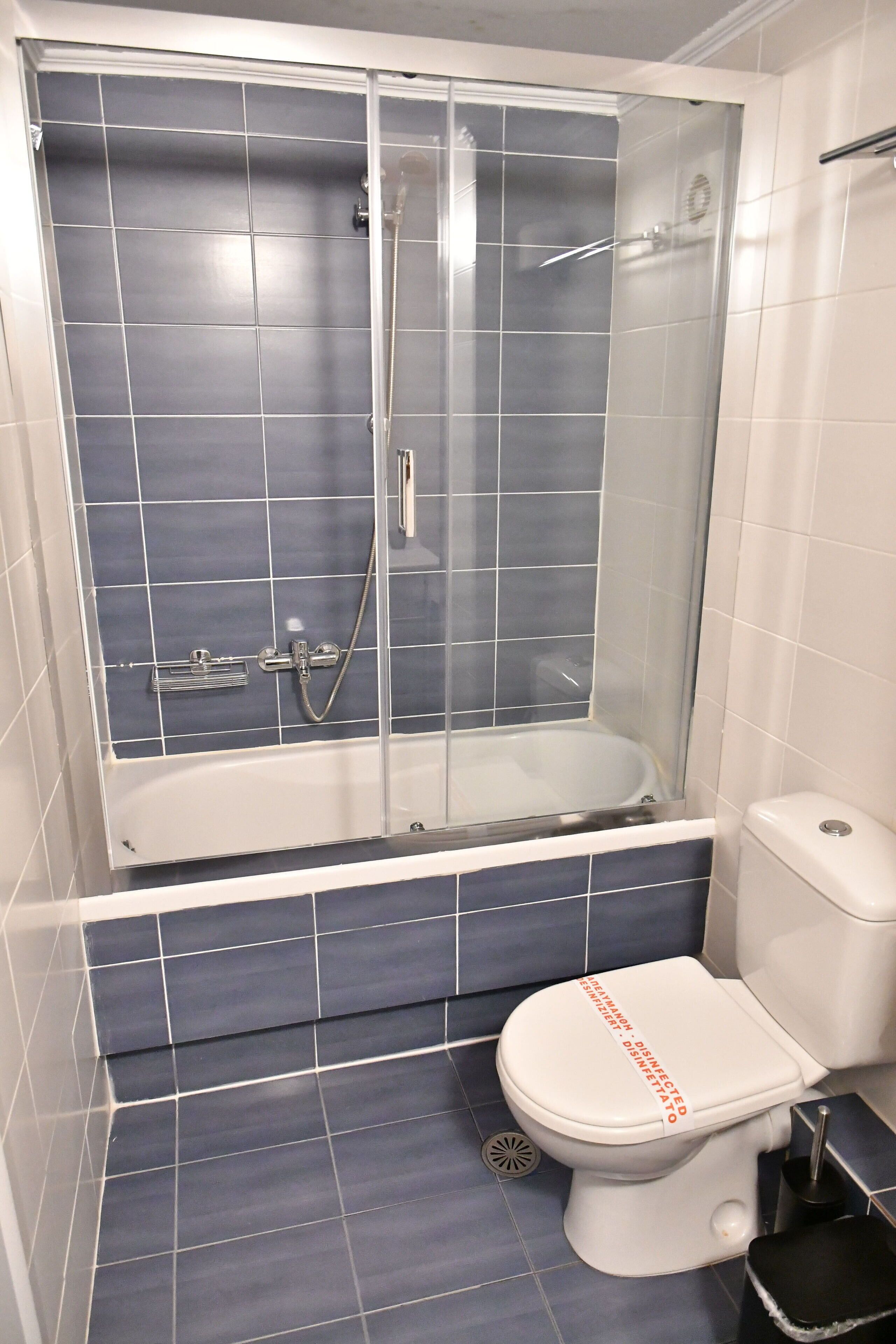 A bathroom with a glass-enclosed shower, a white toilet, and blue-tiled walls.