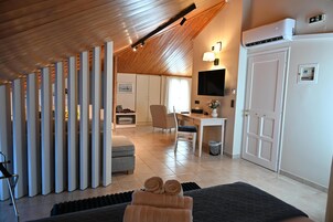 Una habitación moderna con techo de madera, una cama con toallas enrolladas, un escritorio y un televisor fijado a la pared.