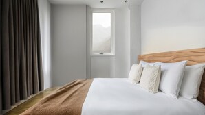 Ein Schlafzimmer mit einem großen Bett, einem Holzkopfende und einem Fenster mit Bergblick.