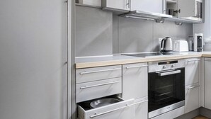 Eine moderne Küche mit Edelstahlgeräten, weißen Schränken und einem Holzboden mit Fischgrätmuster.