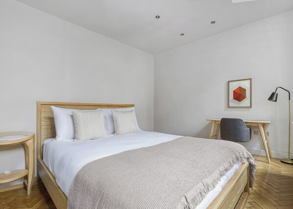 A modern bedroom with a wooden bed, a desk, and a chair.