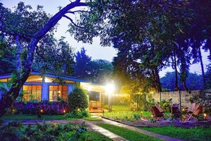 Une maison avec un porche, entourée d’arbres et d’un jardin.