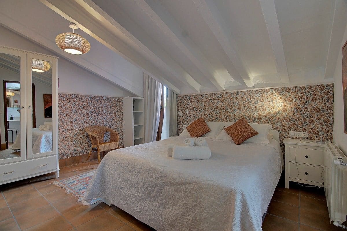 A bedroom with a large bed, a wardrobe, a chair, and a nightstand.