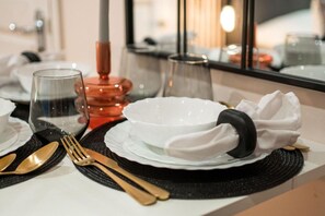 A table set with white plates, a glass, a red candle, and gold cutlery. - 5minwalk2 Bakerstreet/centrallnd (London)