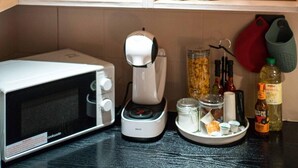 A kitchen with wooden cabinets, a microwave, a coffee maker, and various kitchen utensils and dishes. - 5minwalk2 Bakerstreet/centrallnd (London)