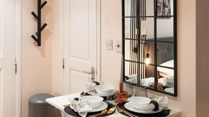 A compact dining area with a white table, three grey upholstered stools, and a mirror above the table. - 5minwalk2 Bakerstreet/centrallnd (London)