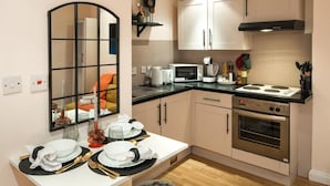 A compact kitchen with a microwave, stove, and a large mirror. - 5minwalk2 Bakerstreet/centrallnd (London)