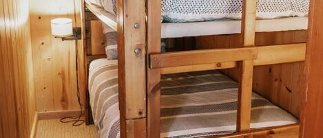 A wooden bunk bed room with a carpeted floor and a wall-mounted light fixture.