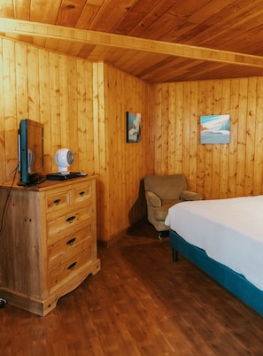 A wooden-paneled room with a bed, a chair, a dresser, and two framed pictures on the wall. - The Inn at Arch Cape (Arch Cape)