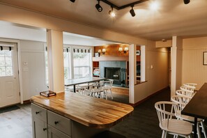 A kitchen with a wooden countertop, white chairs, and a fireplace.