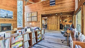A spacious library with wooden walls and floors, a fireplace, and a large collection of bookshelves. - Creekside Cabin: Mountain Views, Fireplace & Sauna (Dumont)