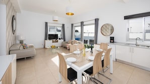 A modern apartment with a dining area, kitchen, living room, and a balcony with a city view. - Villa Janubio With 3 Bedrooms and 2 Bathrooms (Yaiza)
