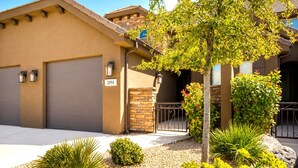 A residential building with a garage door, a number sign, and a landscaped front yard with various plants.