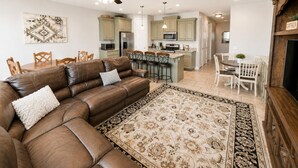 A modern living room with a brown leather sofa, a patterned rug, and a ceiling fan. - Two Heated Pools/Spas, BBQ, Golf Course (Washington)