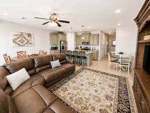A modern living room with a brown leather sofa, a patterned rug, and a ceiling fan. - Two Heated Pools/Spas, BBQ, Golf Course (Washington)