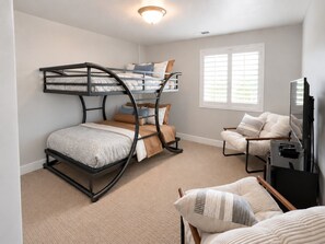 A room with bunk beds, a chair, a television, and a window with blinds. - Two Heated Pools/Spas, BBQ, Golf Course (Washington)