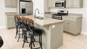 A kitchen with a central island, bar stools, a refrigerator, a microwave, and a stove. - Two Heated Pools/Spas, BBQ, Golf Course (Washington)
