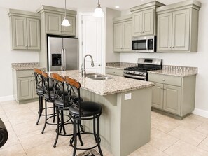 A kitchen with a central island, bar stools, a refrigerator, a microwave, and a stove. - Two Heated Pools/Spas, BBQ, Golf Course (Washington)