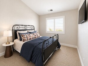 A bedroom with a bed, a bedside table with a lamp, a window with blinds, and a wall-mounted TV. - Two Heated Pools/Spas, BBQ, Golf Course (Washington)