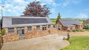A residential property with solar panels, a paved driveway, and a grassy lawn. - The Old Stables 2 - UK46683 (Shipton-Under-Wychwood)
