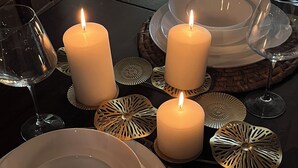 Una tavola apparecchiata per un pasto, con candele, piatti e bicchieri di vino.