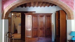 Un corridoio con un armadio in legno, una lampada blu e un pavimento piastrellato.