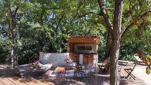 A wooden deck with outdoor seating, a stone wall, and a wooden structure with a slanted roof. - Location Grande Villa au Soleil D'avignon (Châteauneuf-de-Gadagne)