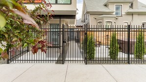 Un lotissement résidentiel fermé, avec une maison moderne, une allée pavée et un petit patio agrémenté d’un banc.