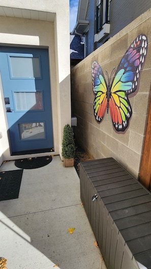 A building entrance with a blue door, a small potted plant, and a colorful butterfly mural on the wall. - LuxuryDenver 750 Sq. Ft. Private Suite - Downtown Denver (Denver)