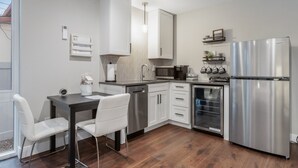 Une cuisine moderne dotée d’appareils électroménagers en acier inoxydable, de meubles blancs et d’un coin repas avec des chaises blanches.