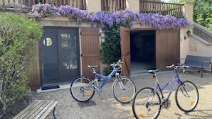 A building with a covered entrance, a wooden bench, and two bicycles parked in front. - La Ponie - Cenves - Gîte (CENVES)