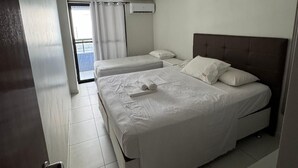 Habitación de hotel con dos camas, un balcón y aire acondicionado.