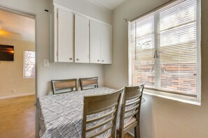 A dining area with a table and chairs, a window with blinds, and a white cabinet above the table. - Central & Quaint Phoenix Condo - Pets Welcome! (Phoenix)