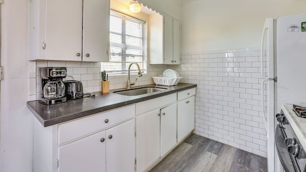 A kitchen with white cabinets, a sink, a stove, and a coffee maker. - Pet-friendly Condo < 1 Mi to Phoenix College! (Phoenix)
