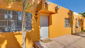 A yellow building with a white door, a small window, and a tree in front. - Pet-friendly Condo < 1 Mi to Phoenix College! (Phoenix)