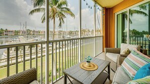 A balcony with wicker furniture, a small table with a plant, and a view of a marina with boats and palm trees. - Bayfront Punta Gorda Condo Rental w/ Pool Access! (Punta Gorda)