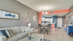A living room with a gray sofa, a coffee table, and a dining area with a kitchen in the background. - Bayfront Punta Gorda Condo Rental w/ Pool Access! (Punta Gorda)