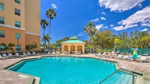 A swimming pool with a green-roofed pavilion, lounge chairs, and palm trees. - Bayfront Punta Gorda Condo Rental w/ Pool Access! (Punta Gorda)